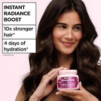 Woman holding Garnier Grape Moisture hair mask beside product benefits