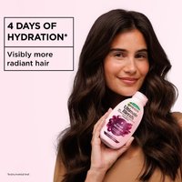 Woman holding Garnier Grape Moisture shampoo beside a hydration claim